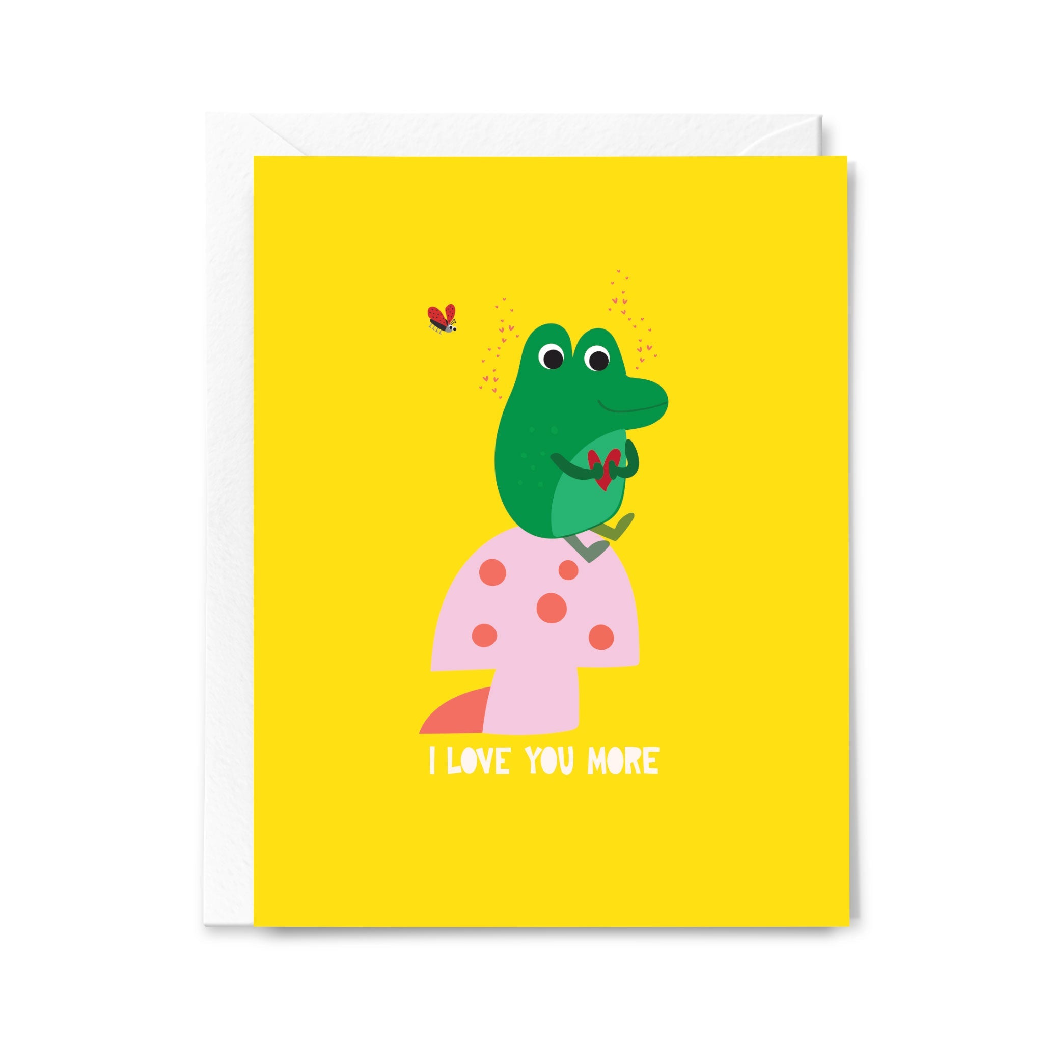 Greeting card with a green frog character on a pink mushroom on a yellow background saying "I love you more"