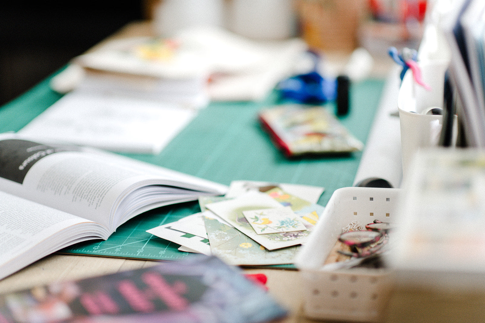 Desk with open book, cards, and stationery items on a green surface